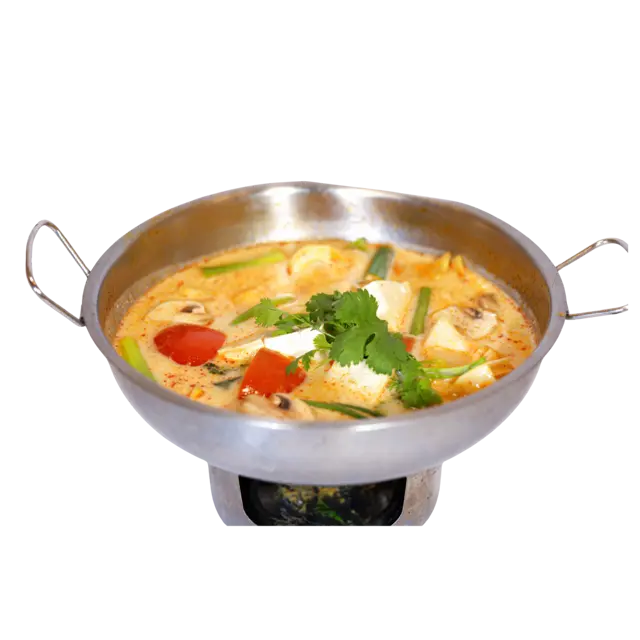 Tom Kha coconut soup simmering in a Thai hot pot over an open flame, with tofu, tomato and mushrooms